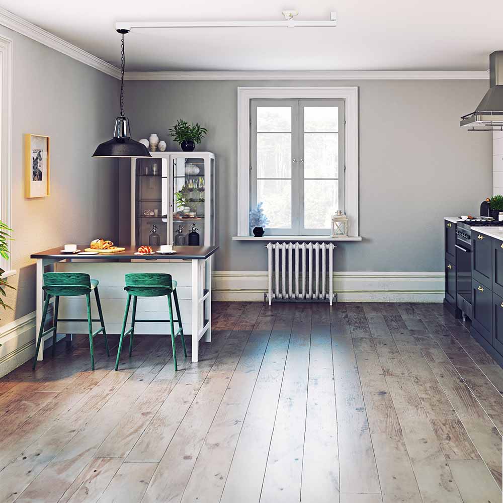 Gråt skandinavisk køkken med en køkkenø, hvor en forlængerarm til pendellamper har ændret placeringen af den sorte pendellampe.