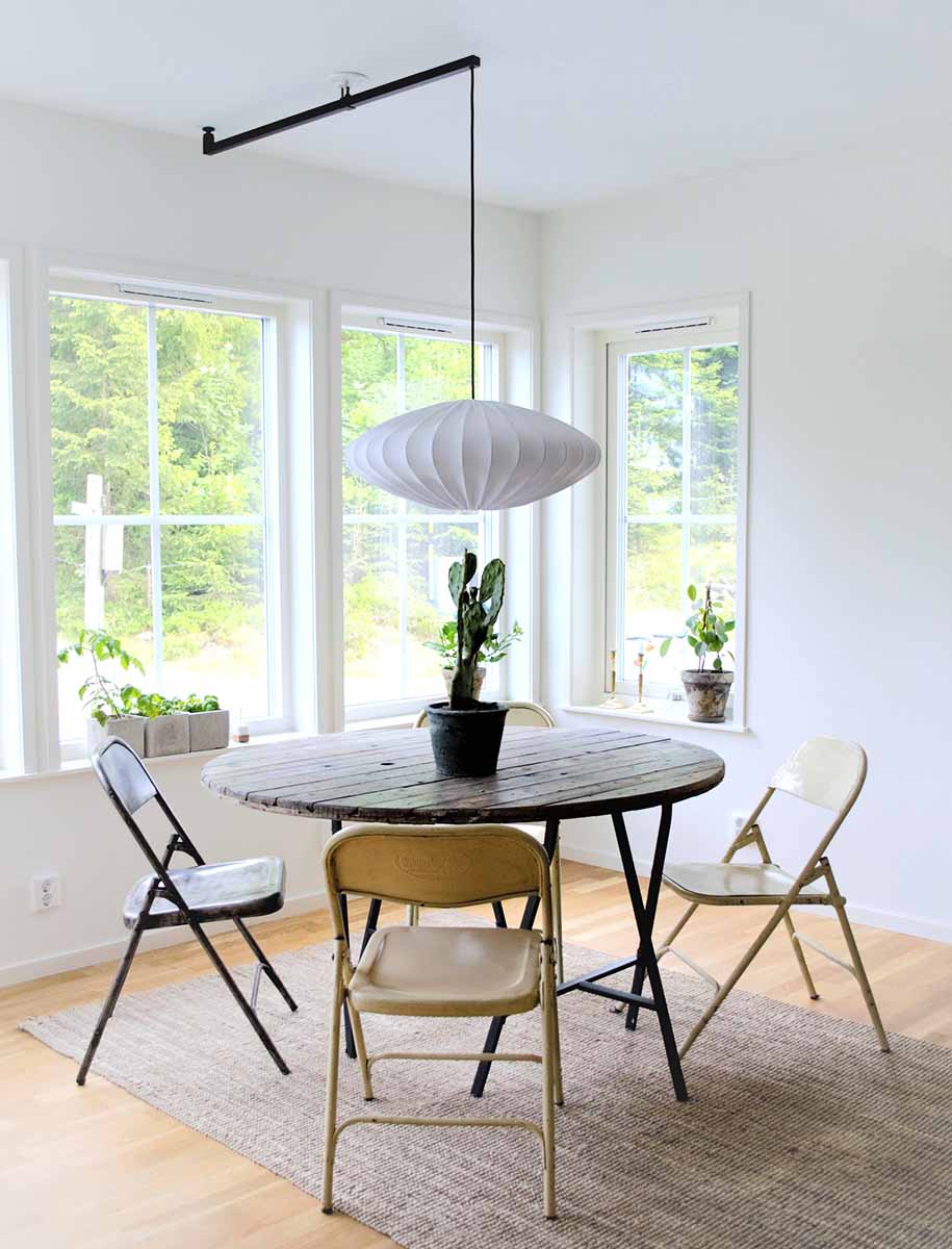 Sort forlængerarm, der har ændret placeringen af en hængende lampeskærm, så den hænger over et bord