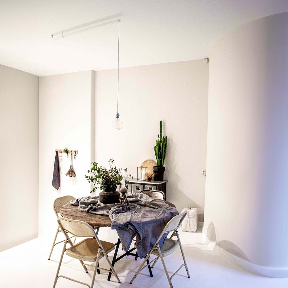 Hvidt rum med en forlængerarm, der ændrer placeringen af en nøgen pære